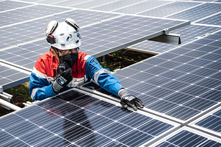 A technician checks a rooftop solar photovoltaic installation at a Pertamina oil and gas refinery in Cilacap, Central Java, in this undated photo.