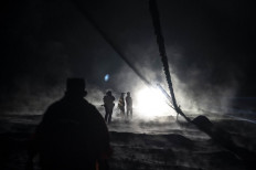 Villagers and rescuers inspect an area covered with volcanic ashes at Sumber Wuluh village, in Lumajang, on December 5, 2021, in an attempt to find survivors or bodies after the Semeru volcano eruption. 