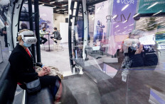 Visitors wearing VR glasses at the stall of VLYR sit inside the cabin of a 'real flight object', which in VR is a flying drone, and are shown a virtual city tour at the ITS World Congress on Intelligent Transport Systems and Services held at the CCH Congress Center in Hamburg, northern Germany on Oct. 13, 2021.