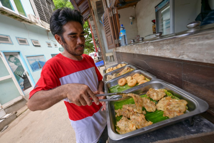 This picture taken on November 22, 2021 shows Indonesian chef Ilhani, a former employee of a Japanese restaurant which closed in 2020 due to the pandemic, preparing fried food for customers on Gili Trawangan resort island. The coronavirus pandemic has shuttered almost all the resorts and restaurants across Indonesia's Gili Islands, famed for their turquoise waters, sandy beaches, and diverse marine life.
