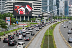 Vehicles drive past an electronic billboard (top left) showing COVID-19 coronavirus related images as they crowd a main road leading out of the capital during the early evening rush hour in Jakarta on November 30, 2021.