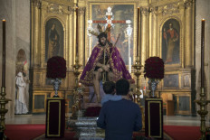 A father and his son looks at a figure of Jesus Christ at San Esteban church, in Seville on March 30, 2021. 2021 is the second consecutive year cancellating Holy Week processions' in Seville due to the coronavirus pandemic.