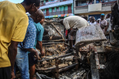 Men pick up aluminum pieces at the site where a tanker truck exploded in Cap-Haitien, Haiti, December 14, 2021. At least 62 people were killed when a gas tanker truck exploded in the Haitian city of Cap-Haitien on December 14, 2021 morning, a local official said, with overwhelmed medics saying the toll was set to rise.