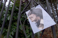 A portrait of the late George Harrison is tied to the railings of the Beatle's former home in Henley-upon-Thames, Britain, November 30, 2001. 
