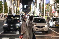Women cross a street at night in Tokyo on Nov. 3, 2021.