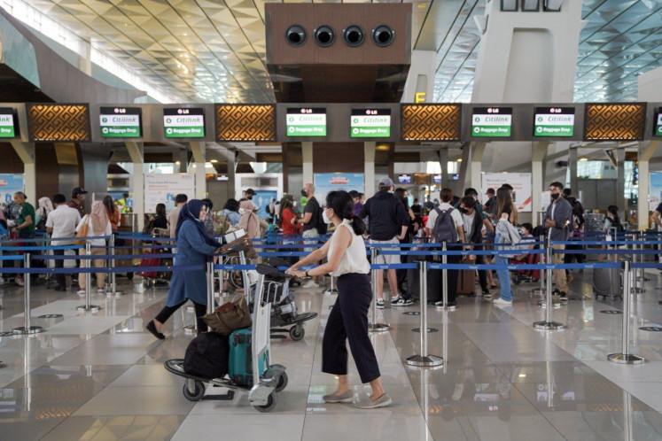 Passengers line up on Dec. 19, 2021 at a row of check-in counters at Soekarno-Hatta International Airport in Tangerang, Banten.