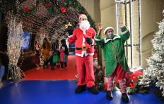 People dressed as Santa Claus and an elf welcome visitors to the Jakarta aquarium ahead of Christmas on Dec. 20.
