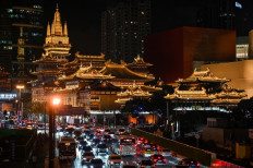 Vehicles make their way along a busy road past the Jing'an Temple in Shanghai on Oct. 14, 2021.