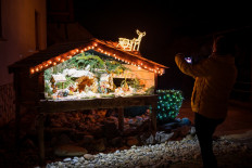 A local resident takes a picture of a nativity scene created by the villagers in Banovci, northeastern Slovenia, on December 21, 2021.