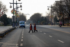 People cross a road in Xi'an in China's northern Shaanxi province on December 31, 2021, amid a Covid-19 coronavirus lockdown.