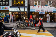 Three men chat as they sit on chairs on a sidewalk in Seoul on Nov. 4, 2021.
 