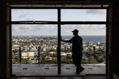 A man looks out over the city from an old bedroom window in the dilapidated Ducor hotel in Monrovia on November 18, 2021.