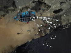 Aerial view of cleaning crews working to remove oil from a beach annexed to the summer resort town of Ancon, northern Lima, on January 22, 2022 after a spill which occurred during the offloading process of the Italian-flagged tanker 'Mare Doricum' at La Pampilla refinery.