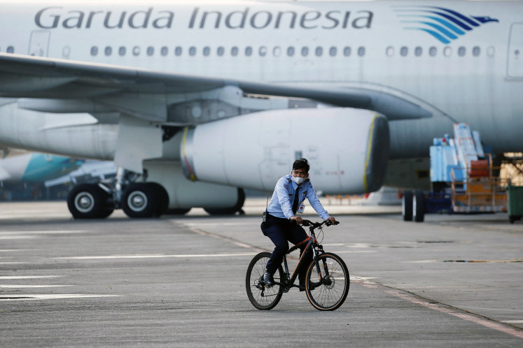 Wings and wheels: A security officer rides a bicycle across the tarmac of Soekarno-Hatta International Airport in Tangerang, Banten, during a routine patrol on Jan. 21, 2022, near the facilities of Garuda subsidiary Garuda Maintenance Facility (GMF) AeroAsia.
