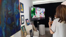 A woman takes pictures of digital art on display at a Tokocrypto T-Hub crypto community space in Seminyak, Bali, on Jan. 21, 2022.