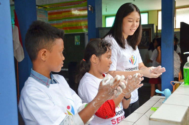 Averina instructs children how to wash their hands during an educational program by Yayasan Indonesia Sehat.