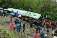 This picture taken in Mangunan, Bantul, Yogyakarta on February 6, 2022 shows residents checking a bus after it crashed killing 13 people and injuring dozens others, police said. 