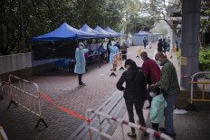 Residents wait in line to test for the COVID-19 coronavirus outside a building placed under lockdown at the Kwai Chung Estate public housing complex in Hong Kong on January 22, 2022, amid a rise in coronavirus cases fuelled by the Omicron variant. 
