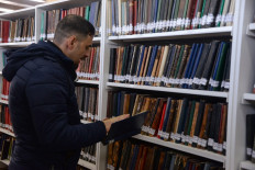 A librarian consults a book from the collection of Mosul central library, founded in 1921, in Iraq's northern city of Mosul, on January 31, 2022.