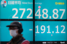 A pedestrian walks past an electronic quotation board displaying the closing share prices of the Tokyo Stock Exchange in Tokyo, Japan, on Feb. 7, 2022.
