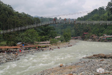 Visitors take pictures from a bridge in Bukit Lawang, which is part of the Gunung Leuser National Park in North Sumatra in this undated photo. Authorities have reopened the national park to visitors, citing the relatively controlled pandemic situation in the surrounding area. 