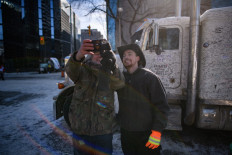 Truck driver Spencer Bautz, 24, R, poses for a photo with a supporters during a protest by truck drivers over pandemic health rules and the Trudeau government, outside the parliament of Canada in Ottawa on February 13, 2022. A white truck parked outside Canada's parliament -- covered in protesters' signatures and scribbled slogans to mark their struggle against Covid restrictions -- has become a must-see for the truckers and supporters hoping their stand goes down in history.