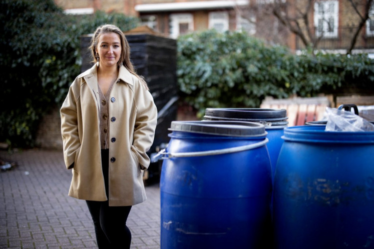Brain behind the brand: UpCircle cofounder Anna Brightman poses on Feb. 10, 2022 next to barrels containing used coffee grounds collected from coffee shops at the cosmetics company’s storage unit in south London. Brightman founded the company in 2016 with her brother Will.