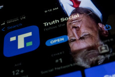 This photo illustration shows an image of former President Donald Trump reflected in a phone screen that is displaying the Truth Social app, in Washington, DC, on February 21, 2022.