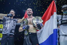 Dominant Champion: ONE light heavyweight and middleweight world champion Reinier de Ridder (center) holds two belts as he celebrates a victory inside the ONE Championship circle. 