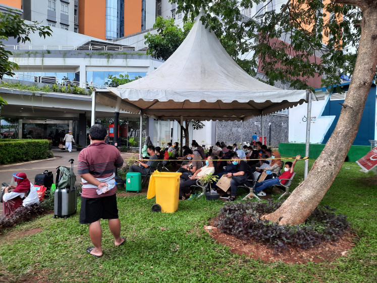 New COVID-19 patients wait under a tent to be called up for registration at the Athletes Village quarantine facility in Kemayoran, Central Jakarta, in this file photo taken in February 2022.