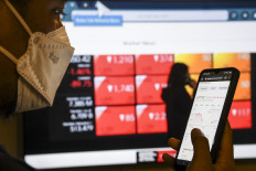 A man checks stock prices on a smartphone in Jakarta on Feb. 24, 2022. The IDX Composite index was among several Asian indices posting cautious gains on Thursday.