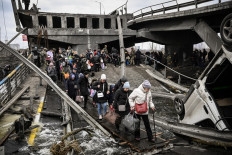 People cross a destroyed bridge as they evacuate the city of Irpin, northwest of Kyiv, during heavy shelling and bombing on March 5, 2022, 10 days after Russia launched a military in vasion on Ukraine.
