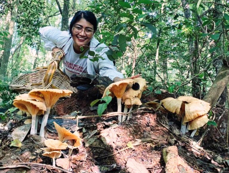 Fungi enthusiast: Aisha Kusumasomantri posed with mushrooms in a forest. Her interest in mushrooms was heavily influenced by her parents. (Courtesy by Aisha Kusumasomantri)