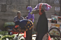 A woman carries a bag of produce at a market in Bekasi, West Java, on Aug. 11, 2021.