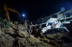 Rescue workers search for victims after a landslide was triggered by heavy rains in the township of Ampang, outside Kuala Lumpur early on March 11, 2022. 