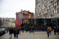 People walk in front of the McDonald's flagship restaurant at Pushkinskaya Square - the first one of the chain opened in the USSR on January 31, 1990 - in central Moscow on March 13, 2022, McDonald's last day in Russia. On February 24, Putin ordered Russian troops to pour into pro-Western Ukraine, triggering unprecedented Western sanctions against Moscow and sparking an exodus of foreign corporations including H&M, McDonald's and Ikea.