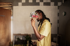 Visual artist vonMash poses for a portrait in his studio in Springs, South Africa, on February 7, 2022 as he covers his face with a painters' palette.