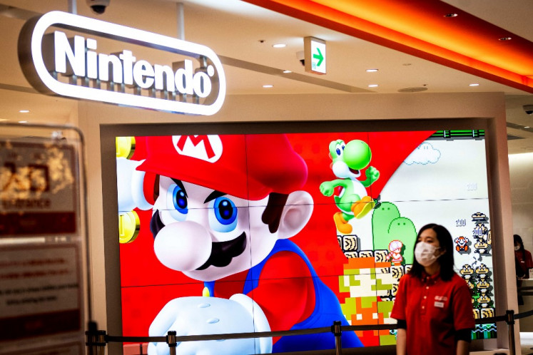 In solidarity: An employee wearing a face mask stands next to a screen displaying a character of Nintendo game Super Mario at a store for Japanese games giant Nintendo in Tokyo on Feb. 3. PlayStation and Nintendo are suspending shipments to Russia, the Japanese gaming giants said Thursday.