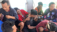 Migrant workers sit on board a boat during a rescue operation in the waters off North Sumatra, where two people died and 26 others went missing after a ferry carrying dozens of migrants sank off the coast of Indonesia on March 19.