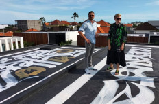 United: Russian artist Pokras Lampas and Ukrainian Alex Shtefan pose with one of nine of Pokras' calligraphy pieces on the rooftop of Alex's villas in Bali on March 16. 