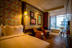 Rustic ambiance: The Grand Deluxe room at the Orient Hotel Jakarta features an open concept bathtub with a full floor-to-ceiling window with a view of the capital city's skyline. (Courtesy of The Orient Hotel Jakarta)