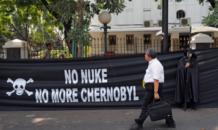A man walks past a banner displayed on a fence of the Energy and Mineral Resources Ministry in Central Jakarta on April 26, 2010, during a Greenpeace demonstration to protest the government’s nuclear power ambitions in conjunction with the 24th anniversary of the1986 Chernobyl disaster in Ukraine, the Soviet Union.