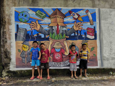 Young target: Four children (two of whom are smoking) pose in front of a mural created by Chusni Thamrin as part of a 1,000 murals parade in Indonesia's major cities. (Courtesy of Yayasan Lentera Anak)