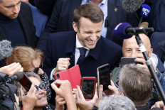 A local resident takes a selfie with French incumbent president and candidate of La Republique en Marche (LREM) party for the presidential election Emmanuel Macron (C) during a campaign visit in Fouras, western France, on March 31, 2022. 