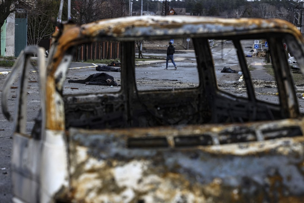 A man walks on a street with several dead bodies on the ground a street in Bucha, northwest of Kyiv.