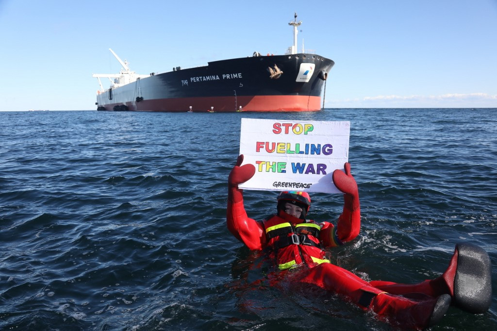 This handout photo made available by Greenpeace shows one of the NGO’s activists holding an antiwar placard in front of the supertanker Pertamina Prime off the coast of Denmark on March 31, 2022.