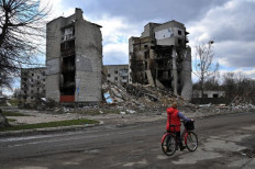 A woman carries her bicycle past destroyed buildings in the town of Borodianka, northwest of Kyiv.