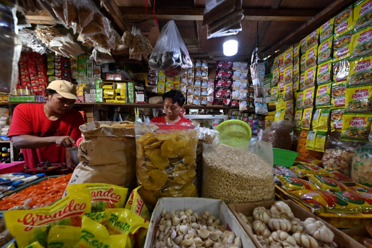 Attendants at a dry goods stall arrange items as they wait for customers on April 3, 2022, at a traditional market in Tangerang, Banten.