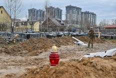 A Ukrainian serviceman stands guard near a mass grave in Bucha, near Kyiv on April 9, 2022.
