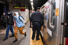 People run out of a subway car as members of the NYPD investigate an incident on an uptown 4 subway after an emergency brake was pulled near Union Square on April 12, 2022 in New York City.